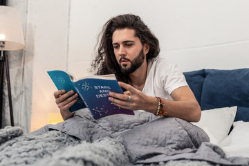 Serious young man reading about stars and destiny