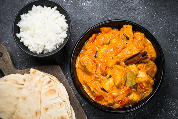 Chicken tikka masala with rice on black top view.