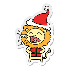 sticker cartoon of a roaring lion with gift wearing santa hat