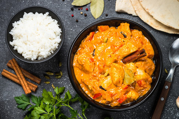 Chicken tikka masala with rice on black top view.