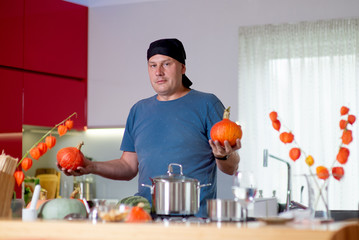  Man cooking  pumpkins with kitchen utensils at kitchen table, cooking in kitchen concept - obrazy, fototapety, plakaty