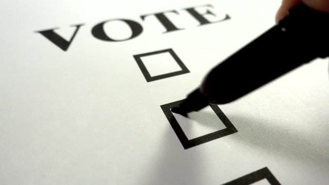 Making a choice by voting. A close up of putting a cross in a box on a voting paper.
