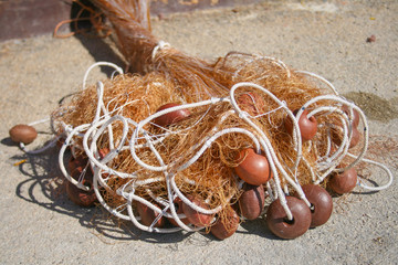 Old fishing net with cords and floats on the beach