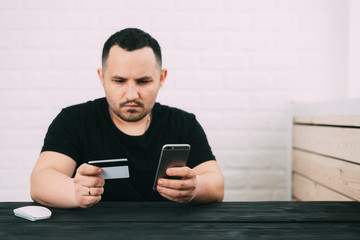 Man paying with credit card on smart phone at home office