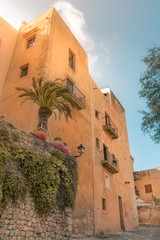 Low angle view of ocher color buildings against blue sky at the old town of Ibiza, Spain. Travel,...
