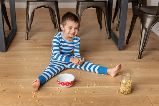 Young boy eating cereal on kichen floor