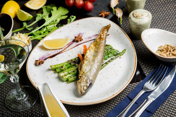 Fried fish with appetizers and white wine. Caucasian cuisine.