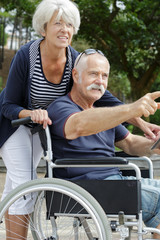 Fototapeta premium elderly couple out for a walk man in wheelchair