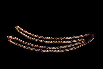 Golden chain weaving non, on a black background with reflection. Isolate, macro, soft focus.