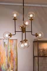 Modern brass chandelier. Pendant lamp with round glass shades and gold-colored copper tubes