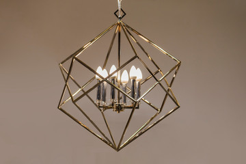 Polygonal chandelier, gold, brass, different shapes of a triangle, inside lamp there are candles. Fashion design chandeliers