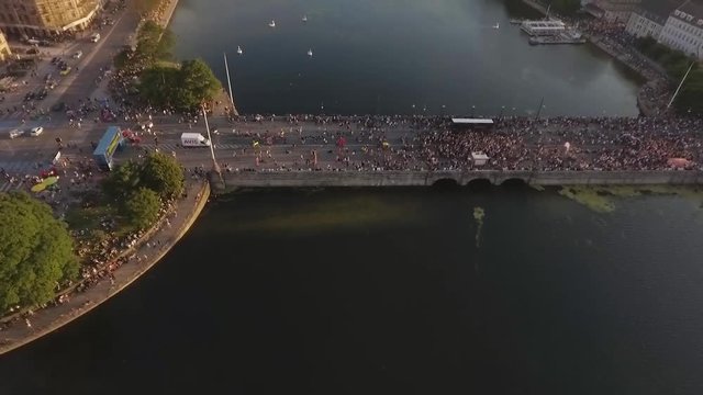 Aerial shot looking down over partying crowd on bridge Dronning Louises Bro flying away revealing the city view and lake during sunset at Distortion Music Festival