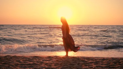 Beautiful girl jumping on the sea coast at sunrise
