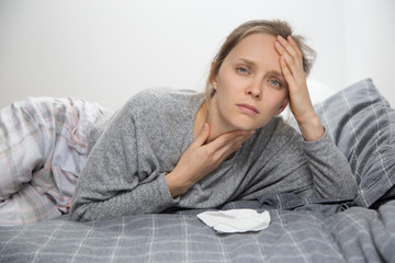 Naklejka premium Tired sick womanin bed, having sore throat, looking at camera