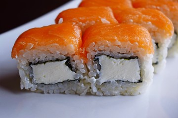 Delicious fresh rolls, Philadelphia, on white plate and black background.