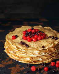 Russian pancakes with berries in front of dark background. Pancake week - the ancient Slavic festival of seeing off the winter