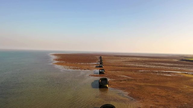 Aerial sequence featuring derelict WWII barges along the Essex coastline. Situated along the Blackwater River, part of the Dengie Peninsula and low-lying marshes near Bradwell in Essex.