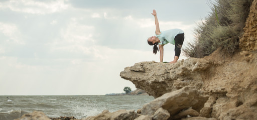 Young woman practicing yoga in nature. Ocean coast. Woman's happiness. Landscape background