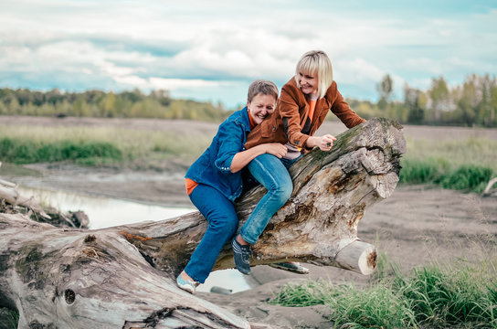 Mature mother with daughter fooling around outdoors. Funny horse racing on log. Family, fun weekend
