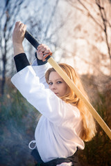 Female warrior. Woman with wooden sword practicing aikido in the snow