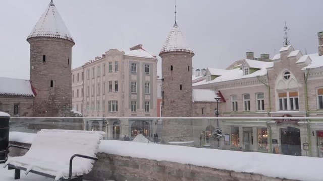 Tallinn Viru gate in old town during a snowfall in winter with a bench in the foreground