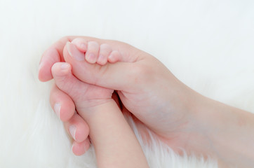 Mother holds babys hand