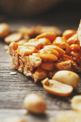 Sweets bar of peanuts on a vintage background with burlap. Delicious oriental sweets Gozinaki from sunflower seeds, sesame and peanuts, covered with honey with a shiny icing