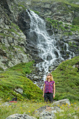 Naklejka na ściany i meble girl tourist in mountain waterfall on the background