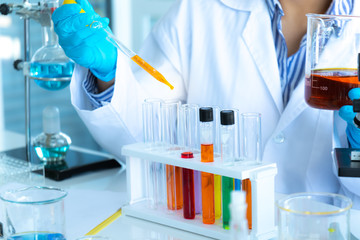 Scientists researching in laboratory. Professional science focus pipetting solution into the glass...