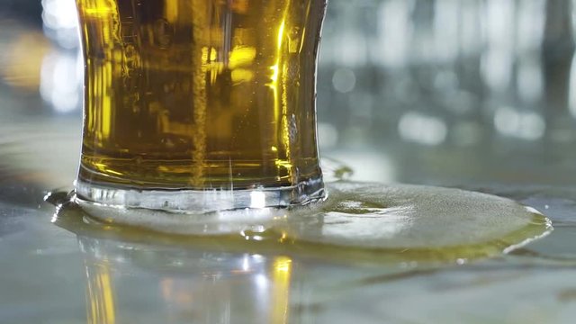 Light beer spilling over side of glass and onto the white counter-top