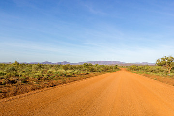 Fototapeta na wymiar Red Australian Rural Road with Cloudy Blue Skies, Western Australia