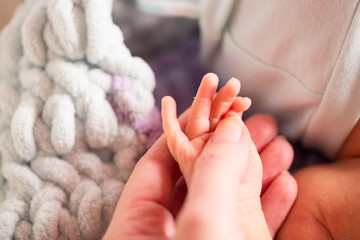 Mom holds t palm of  newborn. Fingers of a child. Mom strokes child's hand.