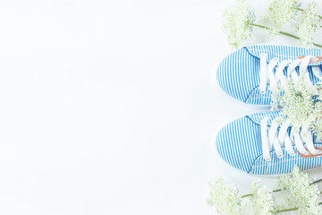 summer shoes and white delicate flowers on white background. summer background with sneakers and flowers.