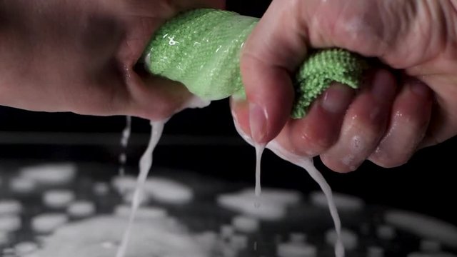 Extreme close up wring out a green rag in slow motion.