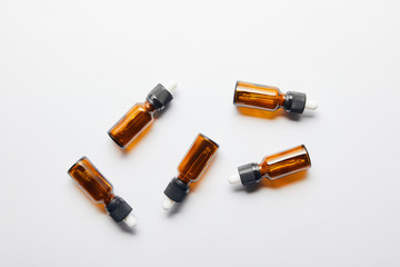 Top view of brown bottles with essential oil lying on grey surface