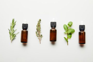 Flat lay with herbs and bottles with essential oil on white background © LIGHTFIELD STUDIOS