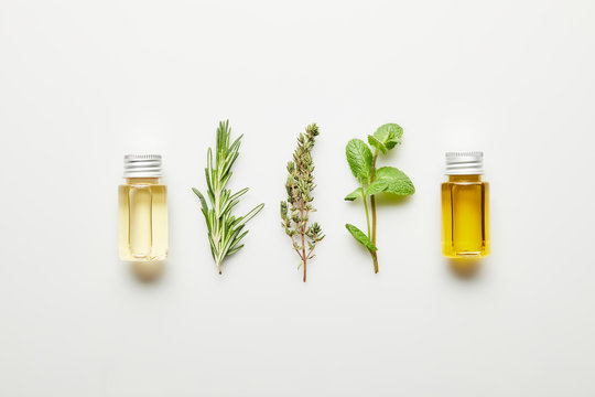 Top view of essential oil, rosemary, thyme and mint on white background