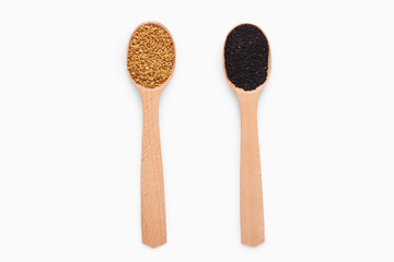 Wooden spoons with fenugreek and black sesame on white