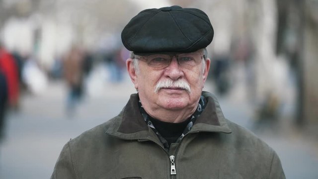 Senior man in a cap thinking about his life in an alley in autumn in slo-mo   