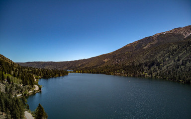 Obraz premium Aerial, drone view of Twin Lakes in the Eastern Sierra Nevada Mountains near Yosemite in Mono County, California with clear blue sky and water, snow capped mountain peaks, green hill sides