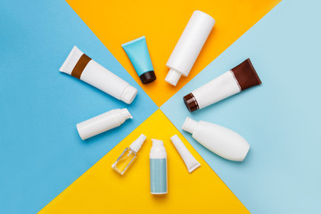 summer skin care cosmetics on yellow and blue background. White bottles of woman cosmetics on yellow. Summer holidays or vacation. Preparation for summer care. Sunscreen protection  products. Sun form