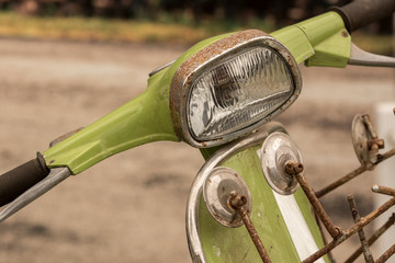 Rusty vintage mod green scooter bike handlebar, mirrors and headlamp.