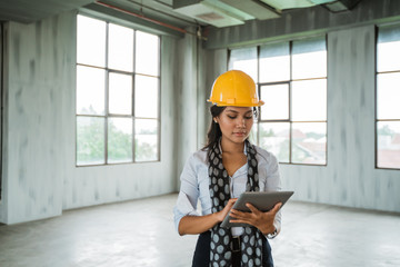woman engineer wearing hardhat hold a digital tablet in the hall space building