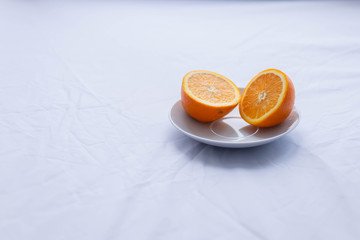 orange cut in half on white plate on white background