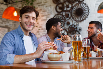 Fototapeta na wymiar Men eating burgers and drinking beer in pub