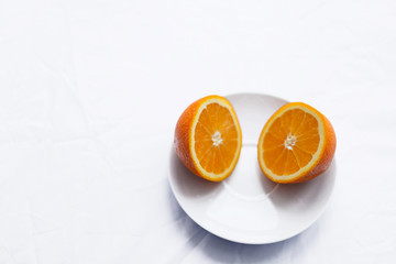 orange cut in half on white plate on white background