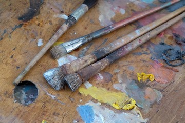 Old brushes and paints on a dirty palette in the artist's studio