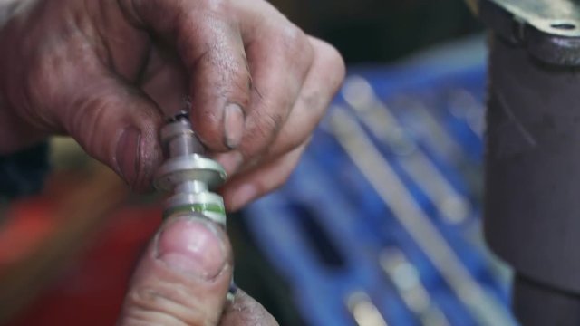 A mechanic repairs small part for a car or truck close-up