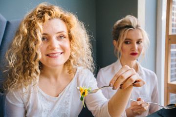 Blond curly american woman eating salad in cafe or restaurant with friend
