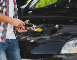 Young man looking under the hood of breakdown car